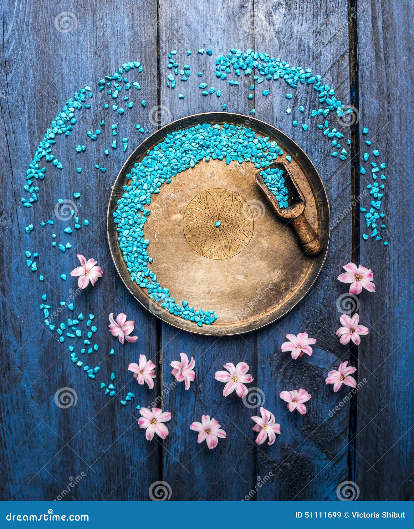 Metallic bowl with sea salt, scoop and flowers on blue wooden table, wellness background, top view, copyspace