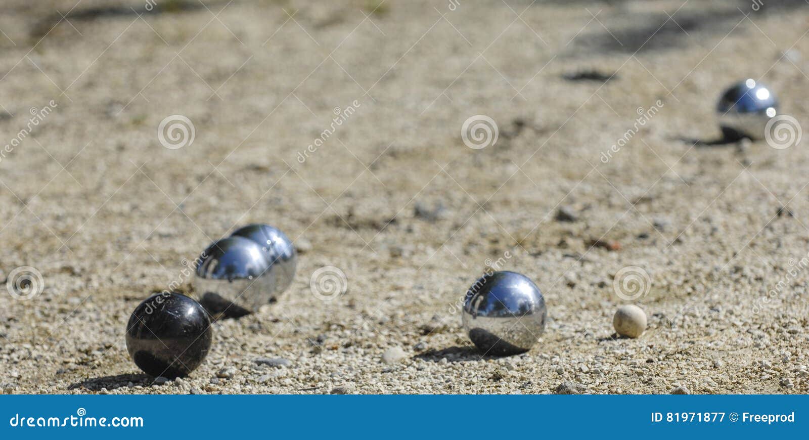 Metal petanque balls and a small wooden jack or cochonnet on sand