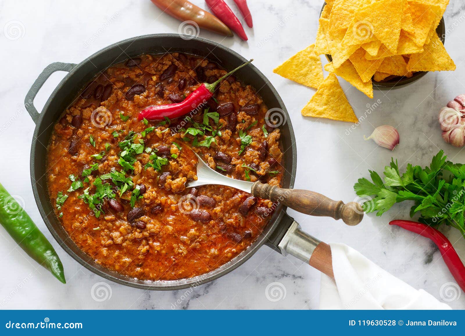 mexican and american food chili con carne served with nachos, pepper and herbs.