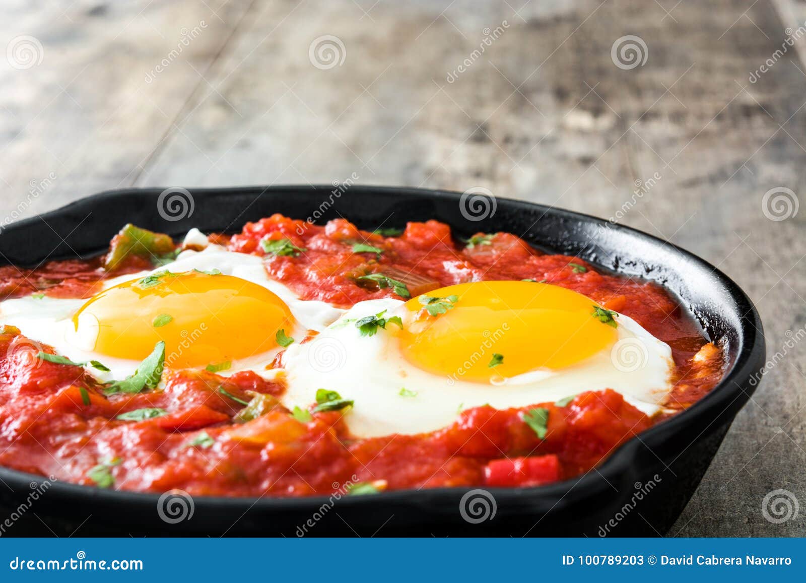 mexican breakfast: huevos rancheros in iron frying pan on wood