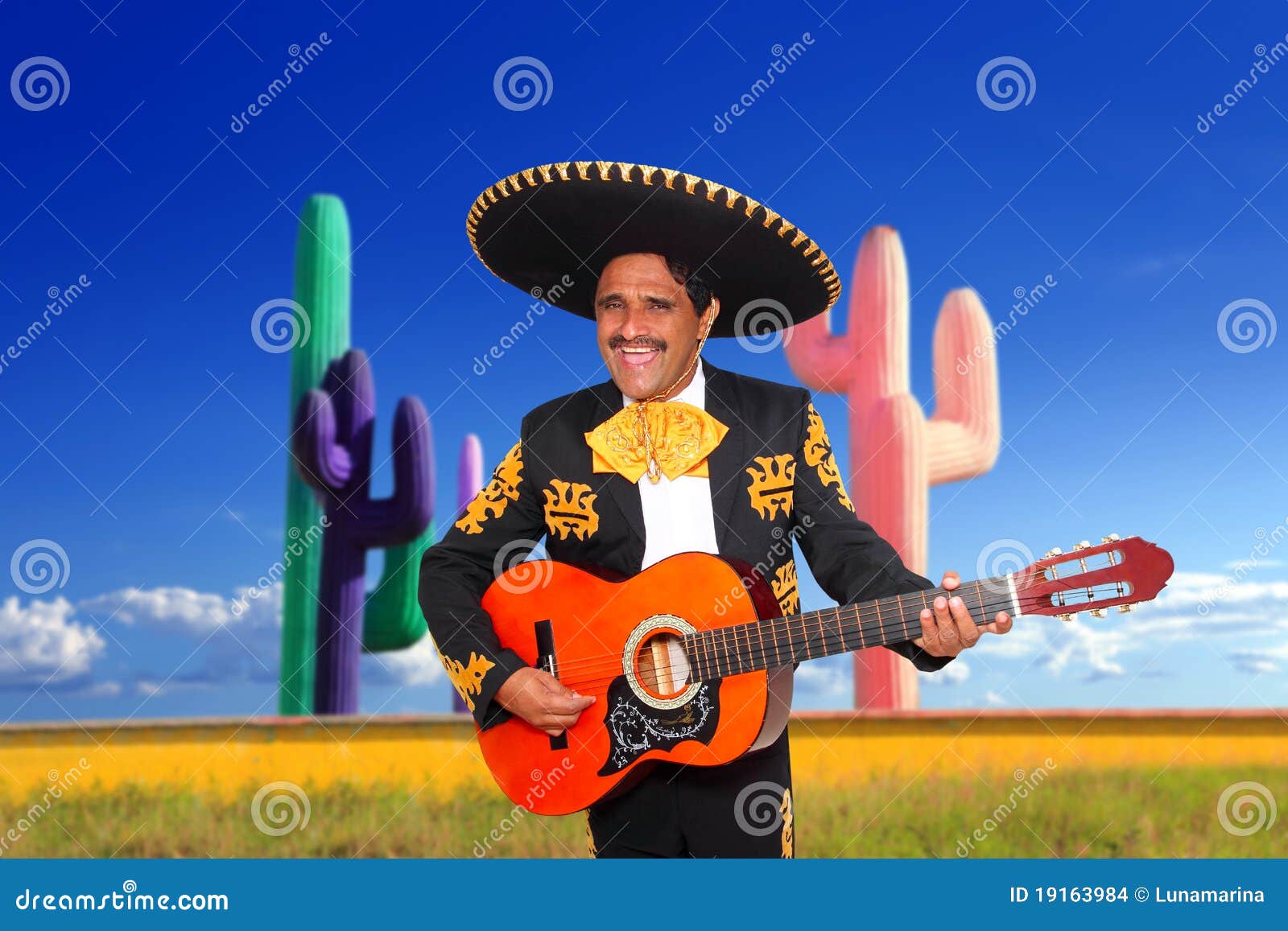 mexican mariachi charro playing guitar in cactus