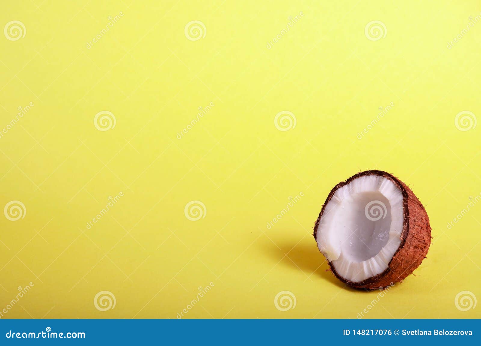 Mezza noce di cocco su fondo giallo Alimento esotico Concetto tropicale di estate copi lo spazio per il vostro testo