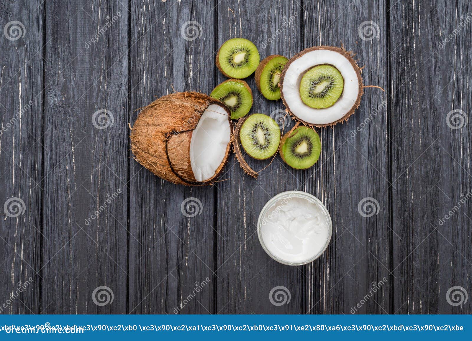 Mezzi noce di cocco e kiwi. Noce di cocco e kiwi dentro sulla tavola di legno grigia