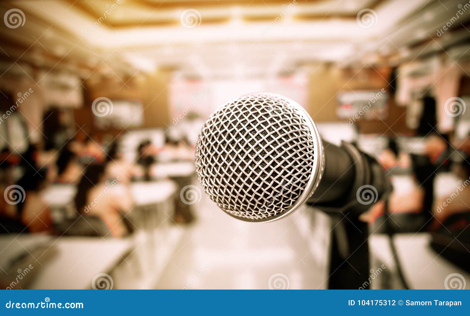microphone on abstract blurred of front podium and speech in seminar room or speaking conference hall light, event meeting