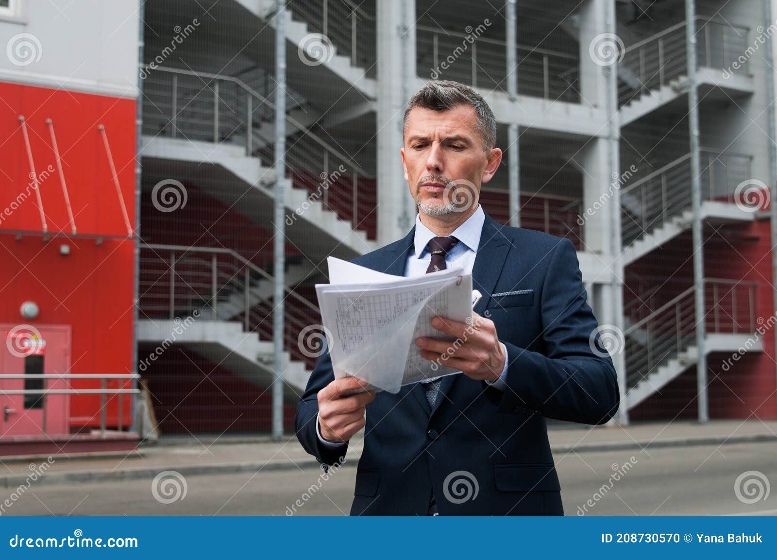 mid adult businessman writing on clipboard in metal industry