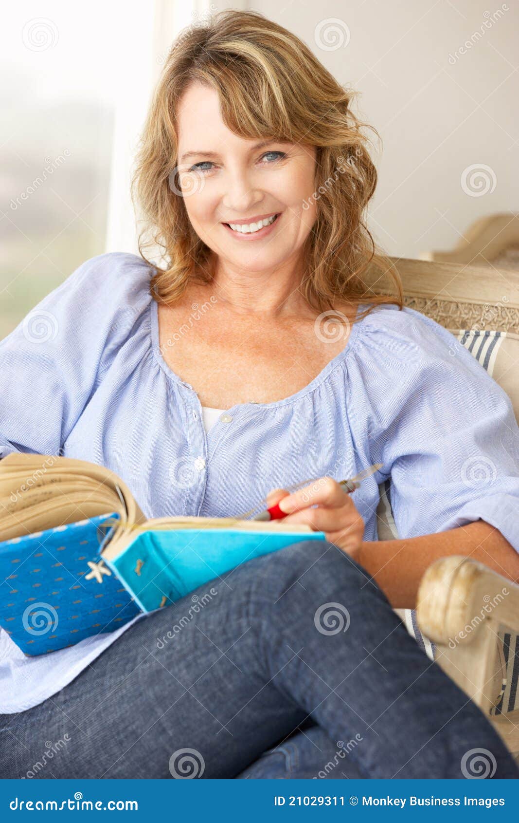 Mid age woman writing in notebook smiling at camera