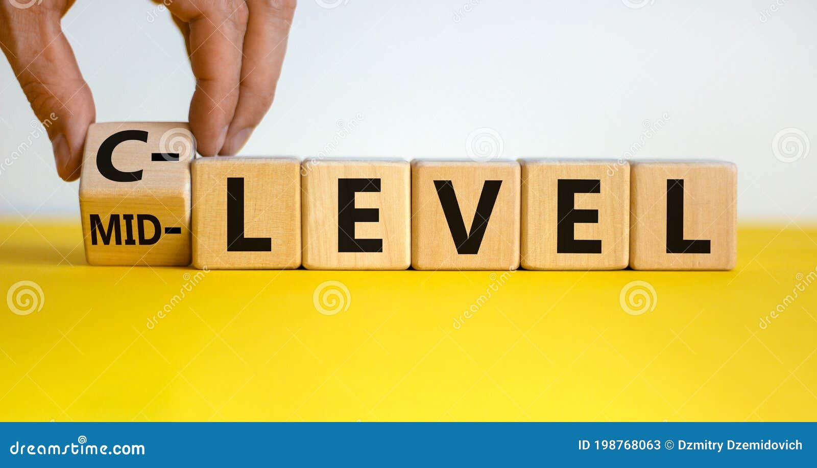 from mid level to c level. hand turns a cube and changes the words `mid level` to `c level`. beautiful yellow table, white