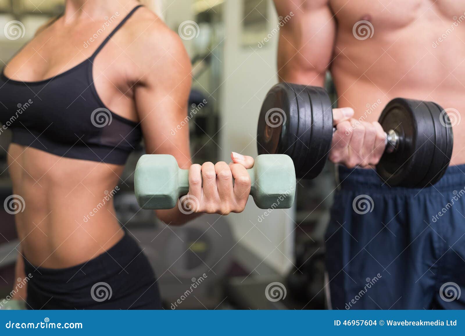 Mid Section of Couple Exercising with Dumbbells in Gym Stock Photo
