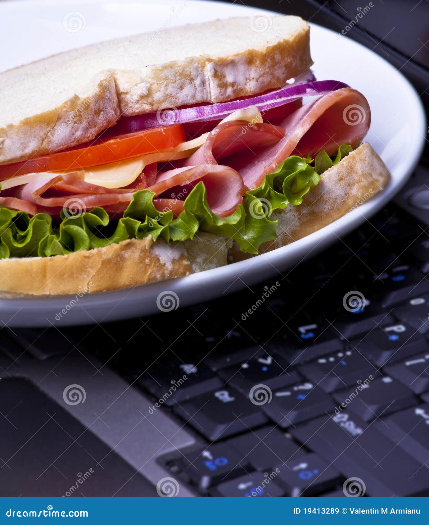 Een plaat met een sandwich op een laptop middagpauze - concept