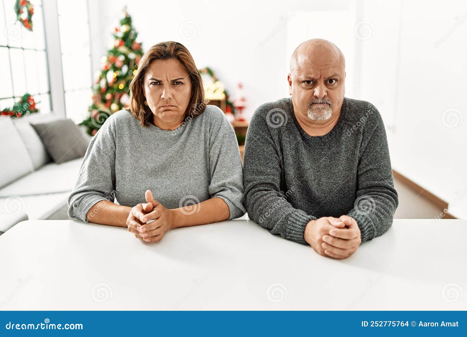 Middle Age Hispanic Couple Sitting On The Table By Christmas Tree middle-age-hispanic-couple-sitting-on-the-table-by-christmas-tree