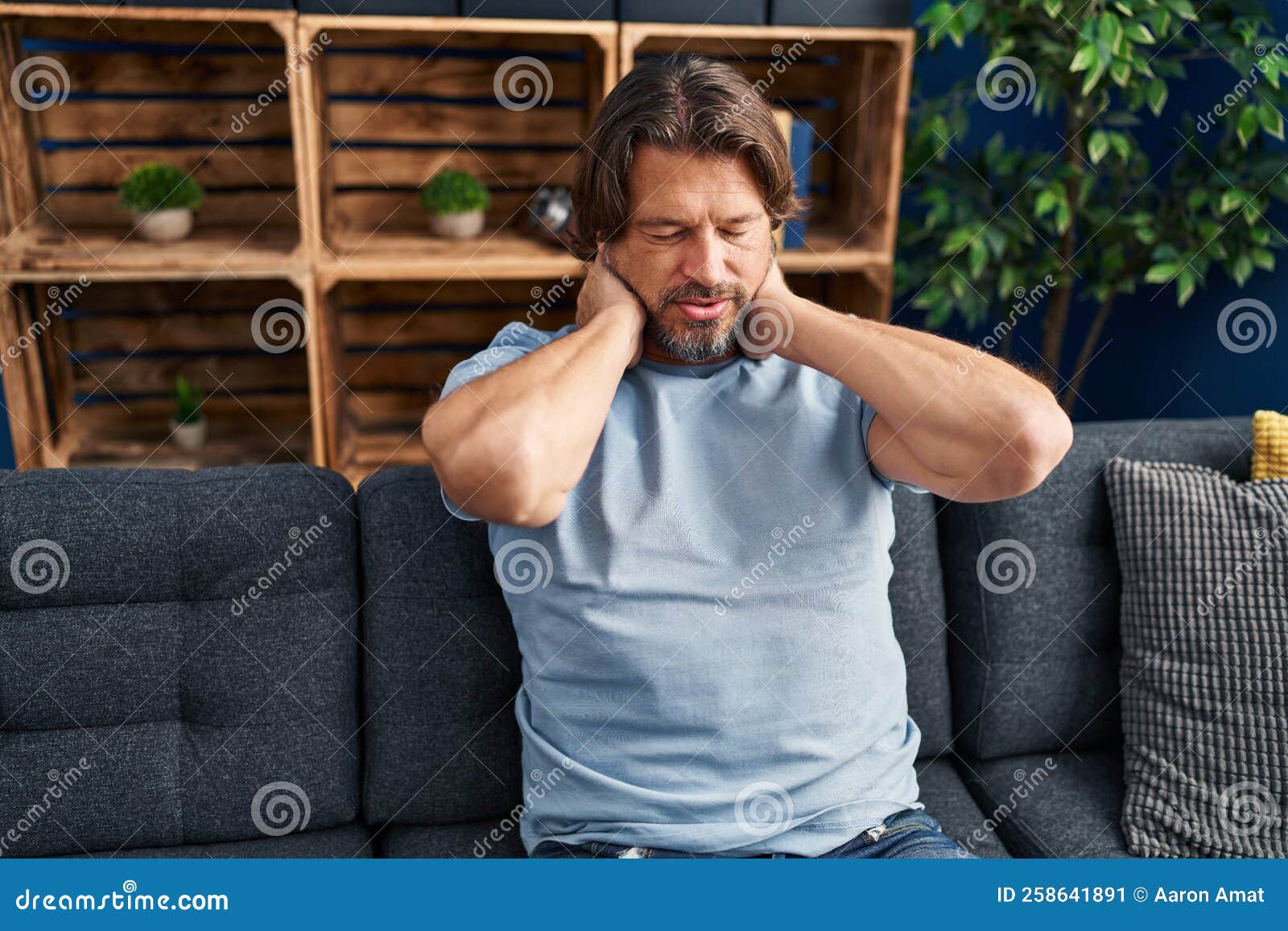 Middle Age Man Suffering for Neck Pain Sitting on Sofa at Home Stock