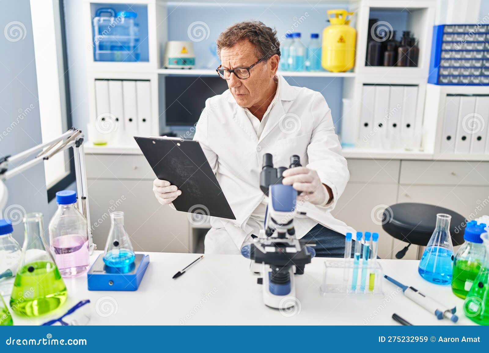 Middle Age Man Wearing Scientist Uniform Using Microscope at Laboratory