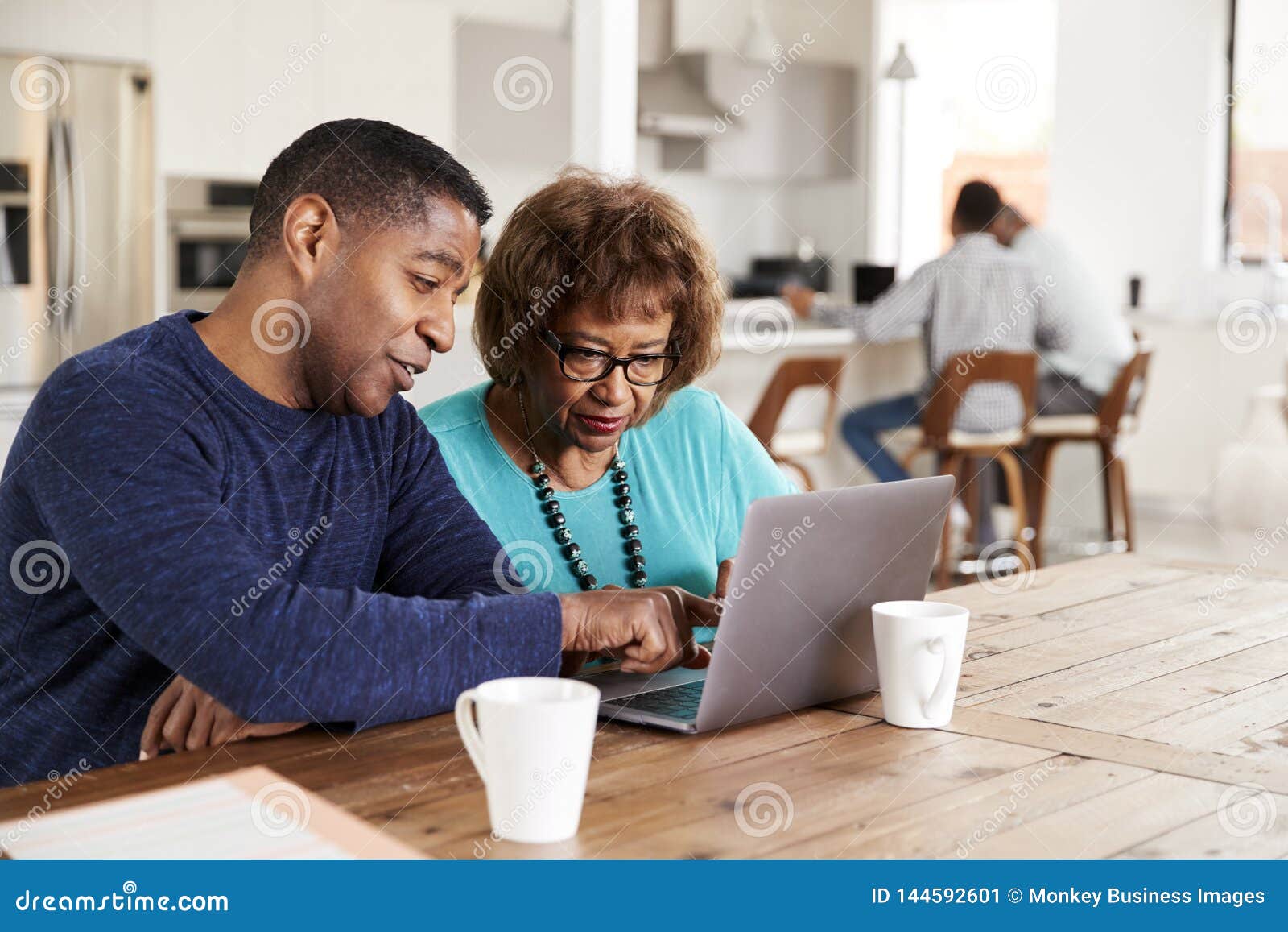 middle aged african american  man helping his mother use a laptop computer at home, close up