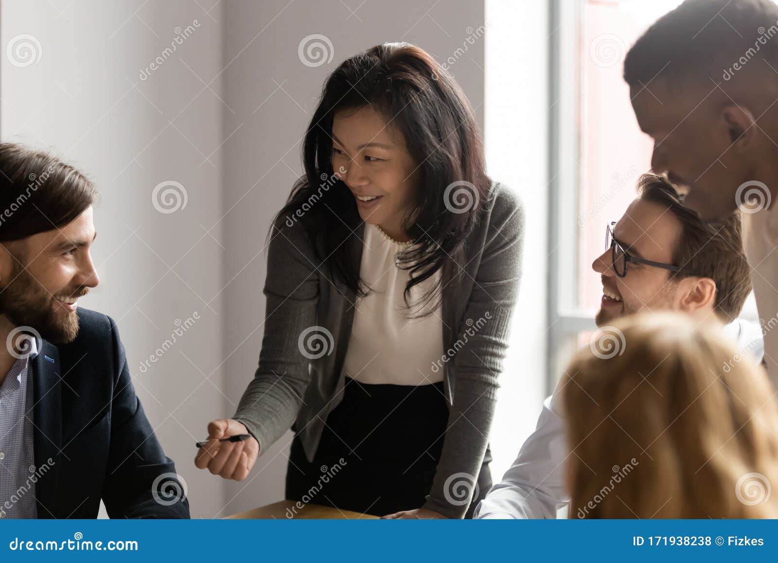 middle aged asian businesswoman talking to diverse colleagues at meeting