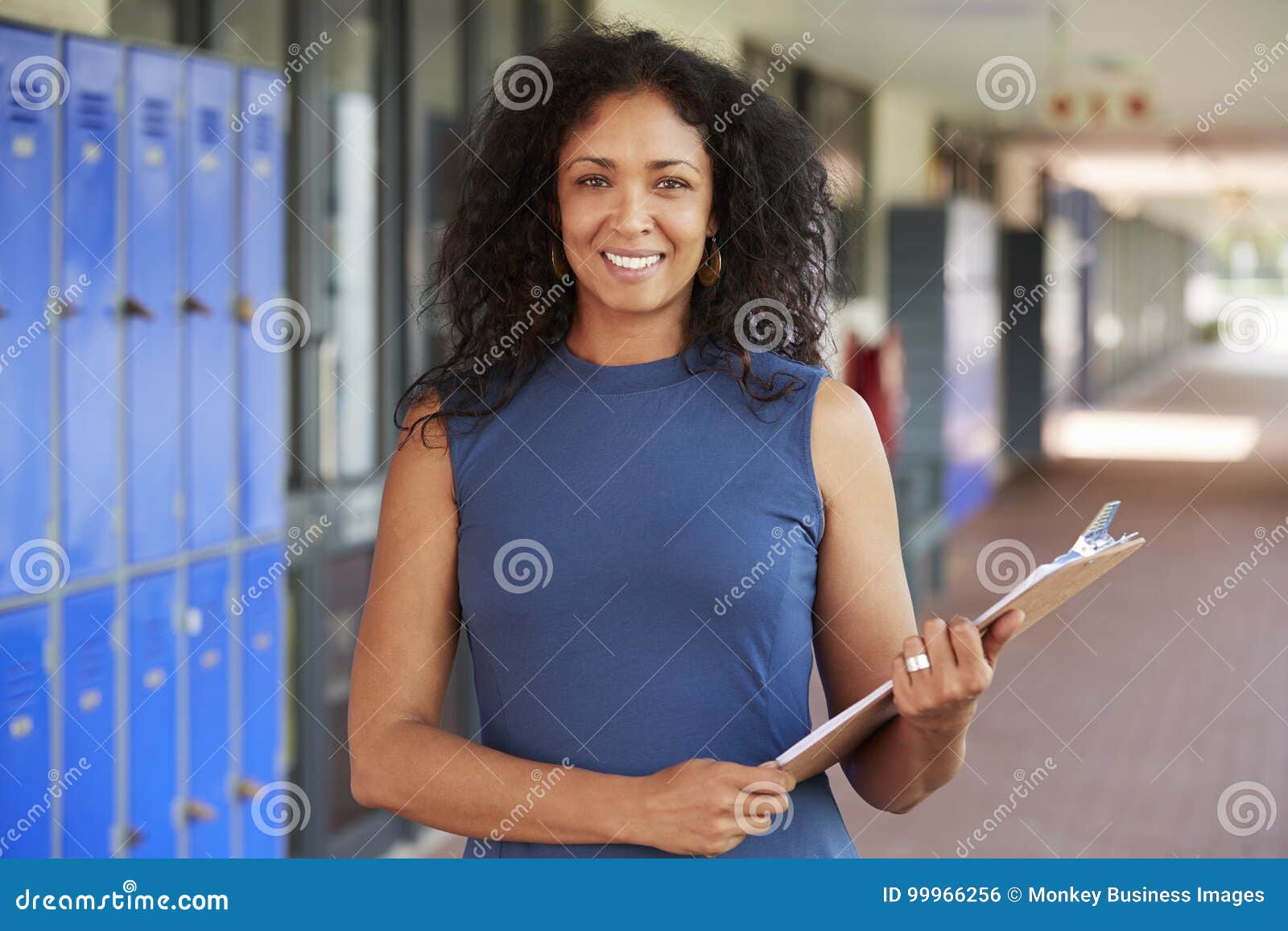 middle aged black female teacher smiling in school corridor