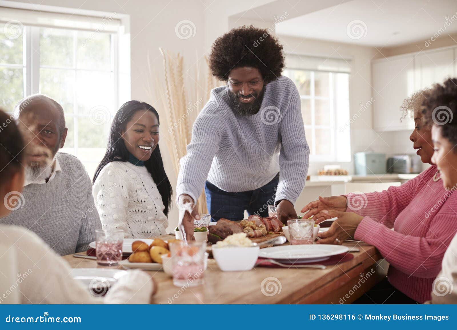 Middle Aged Black Man Bringing Roast Meat To The Table For The Sunday