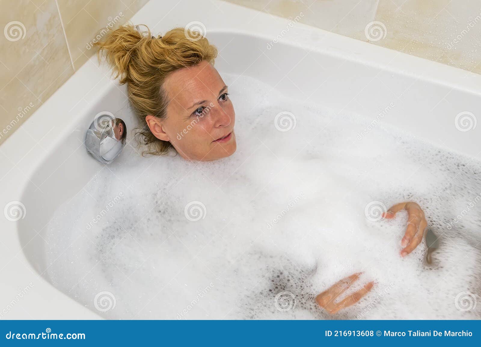 Middle Aged Blonde Woman Relaxes Immersed In The Bathtub Filled With 