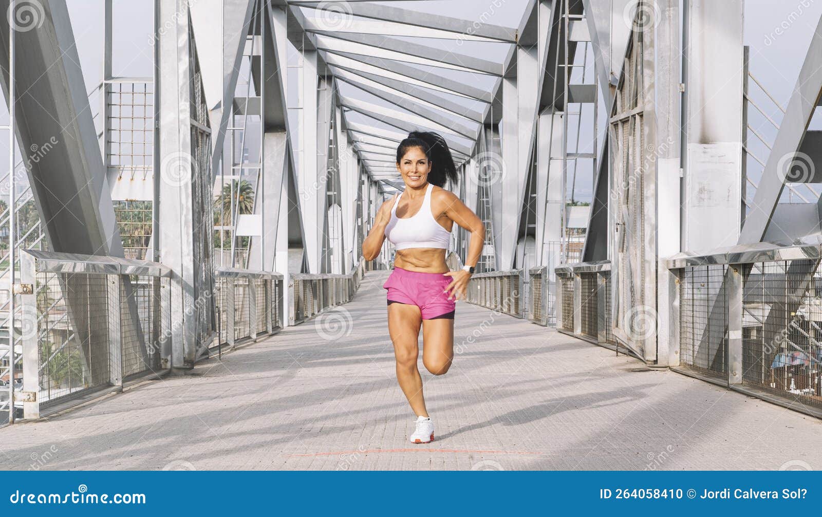 Middleaged Female Athlete Running Across a Bridge Stock Photo Image