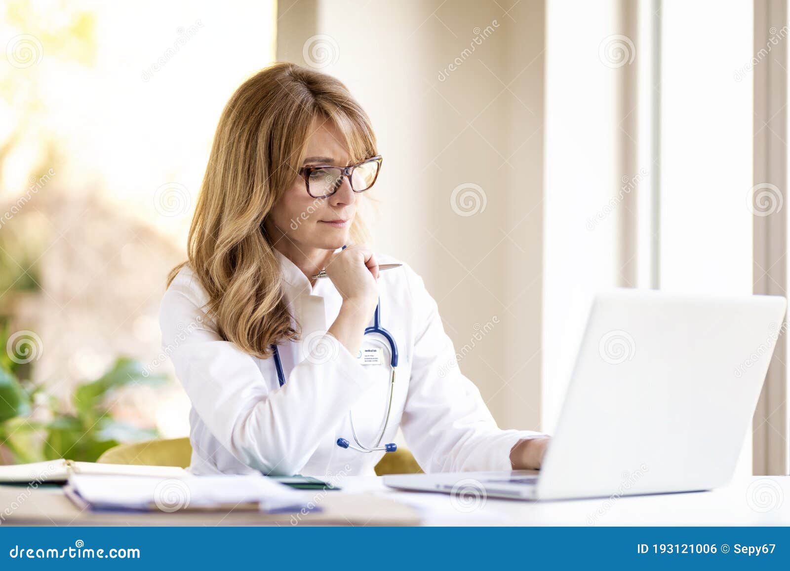 middle aged female doctor working on laptop in doctor`s room