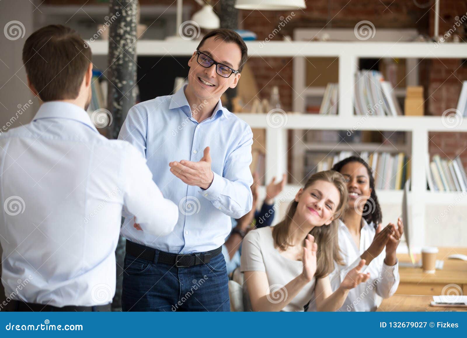middle aged boss, mentor congratulating employee, shaking hand