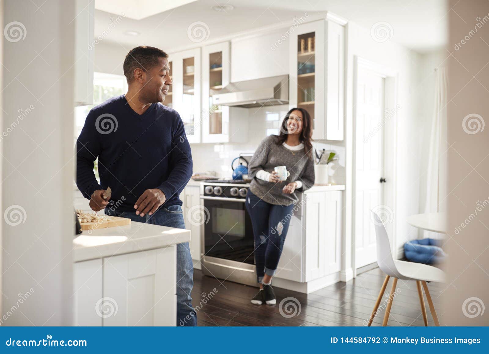 Middle Aged Man Standing At Worktop In The Kitchen Preparing Food