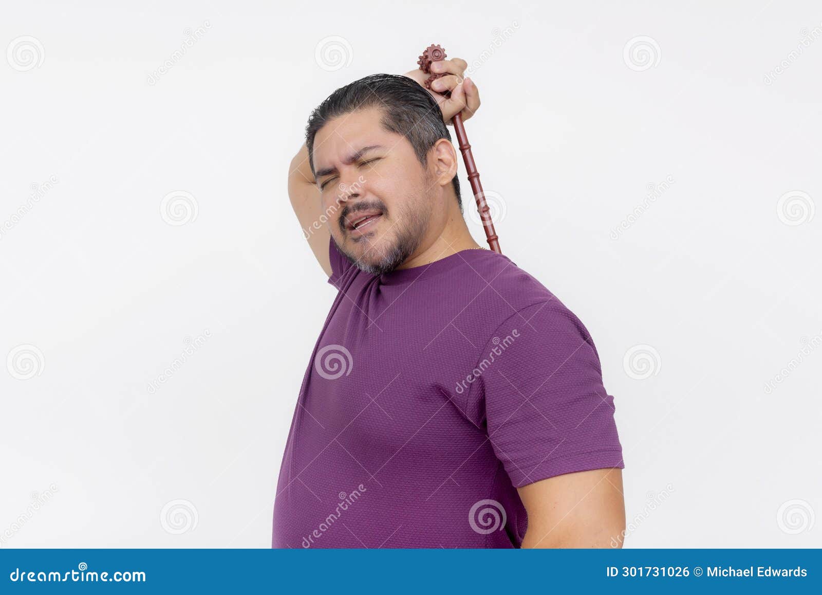 a middle aged man using a backscratcher to scratch and relieve an itch on his upper back. looking satisfied.  on a white