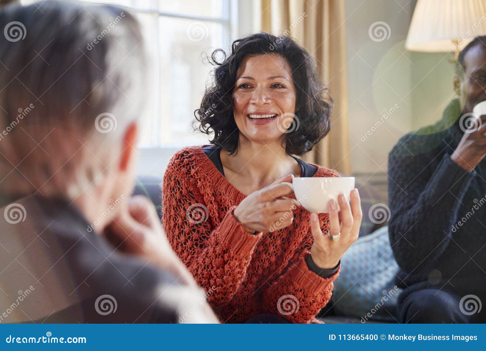 middle aged woman meeting friends around table in coffee shop