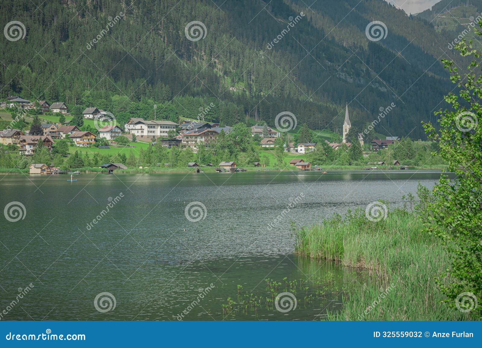 middle part of weisensee in austria, visible church and typical village houses on the banks of picturesque alpine lake. one of