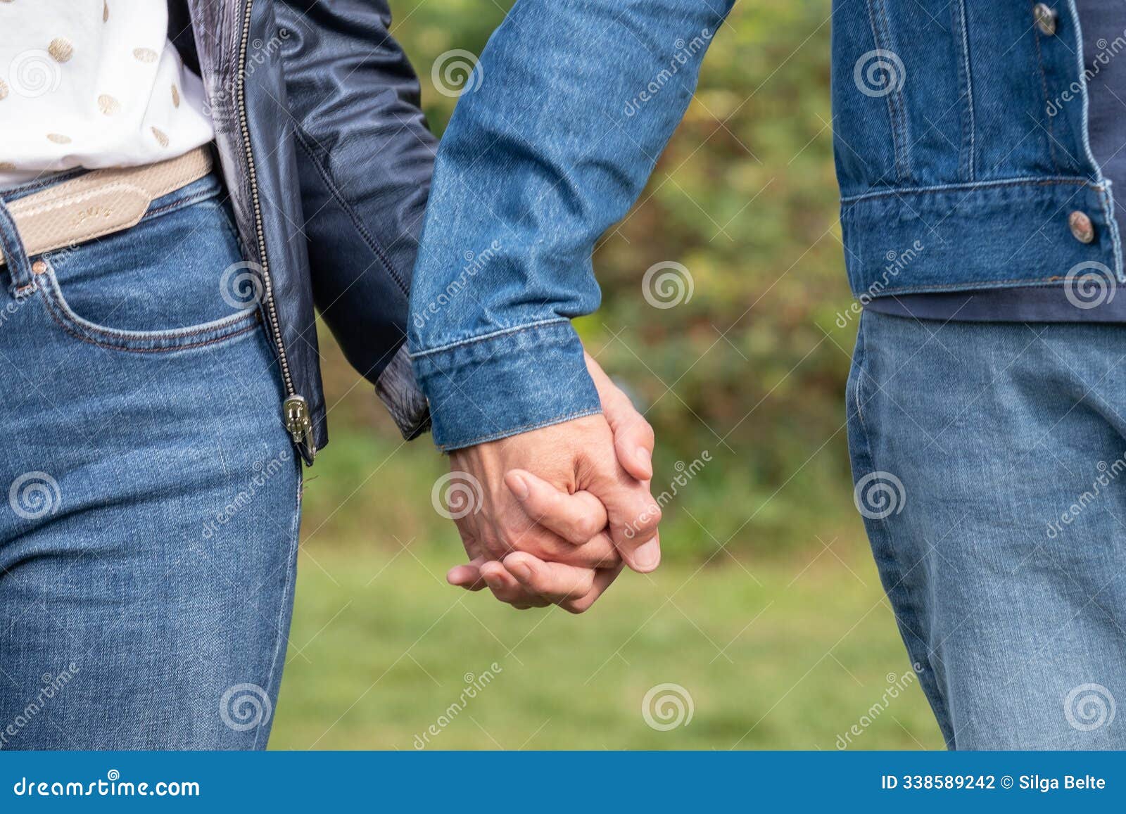 midlife couple holding hands, wearing casual denim clothes, outside in nature, izing support and care, close-up