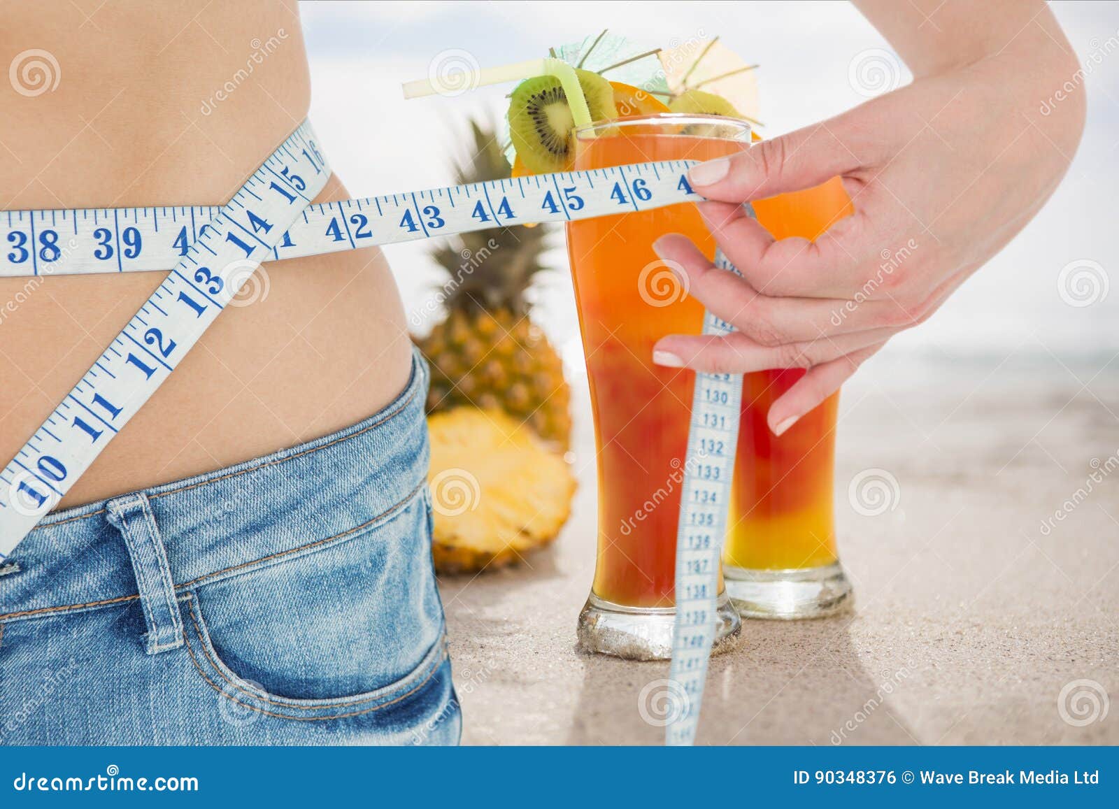 midsection section of woman measuring waist with juices in background