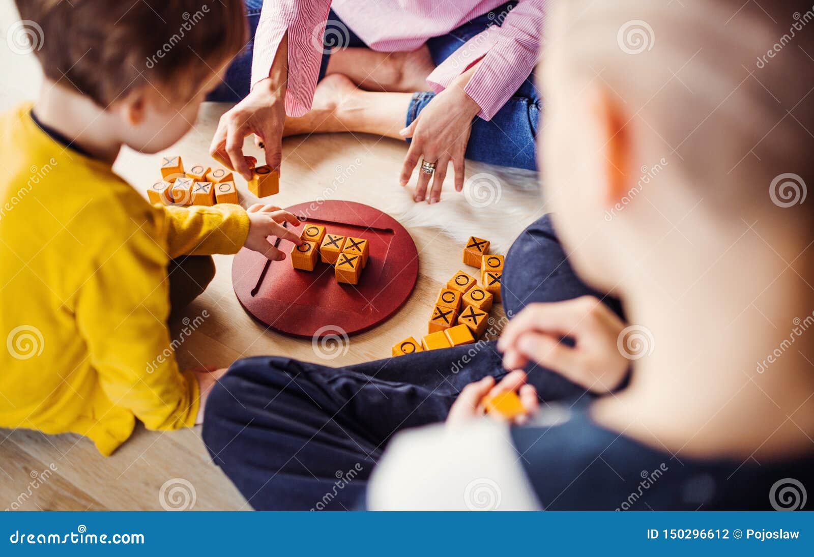 Midsection van moeder met twee kinderen die raadsspelen op de vloer spelen Hoogste mening