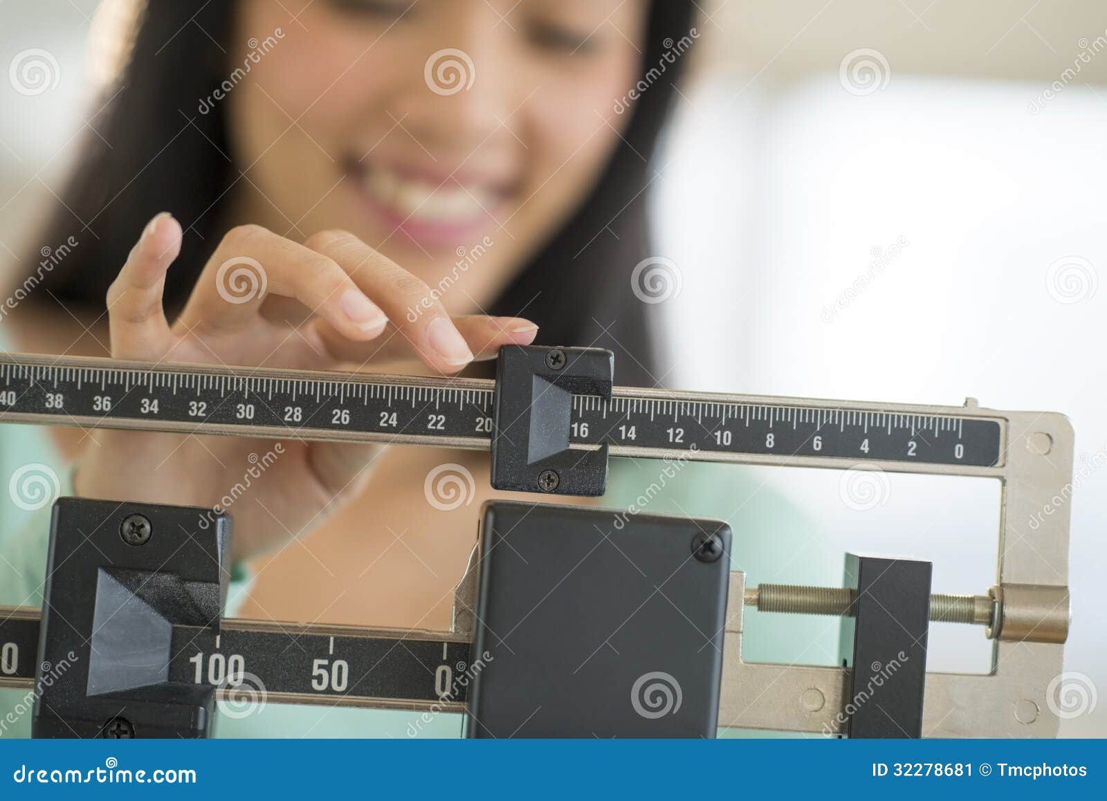 midsection of woman smiling while adjusting weight scale