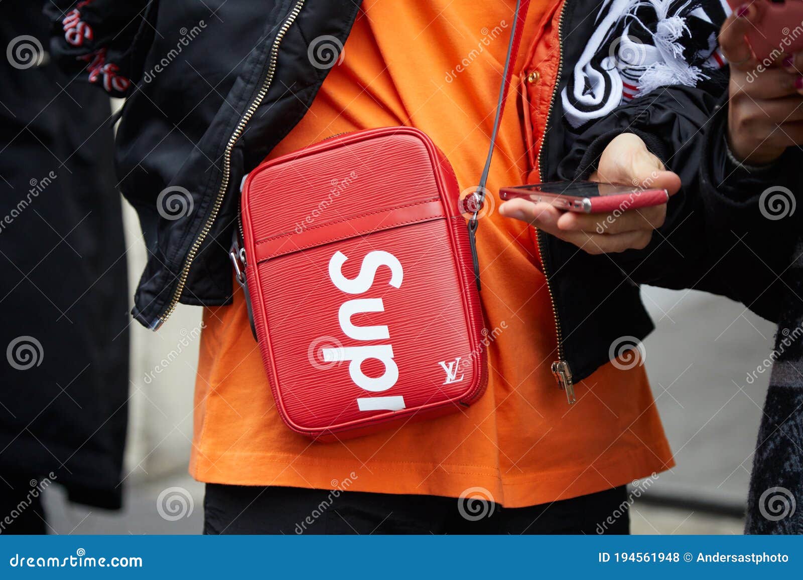Man with Orange Shirt and Red Louis Vuitton Supreme Bag Looking at
