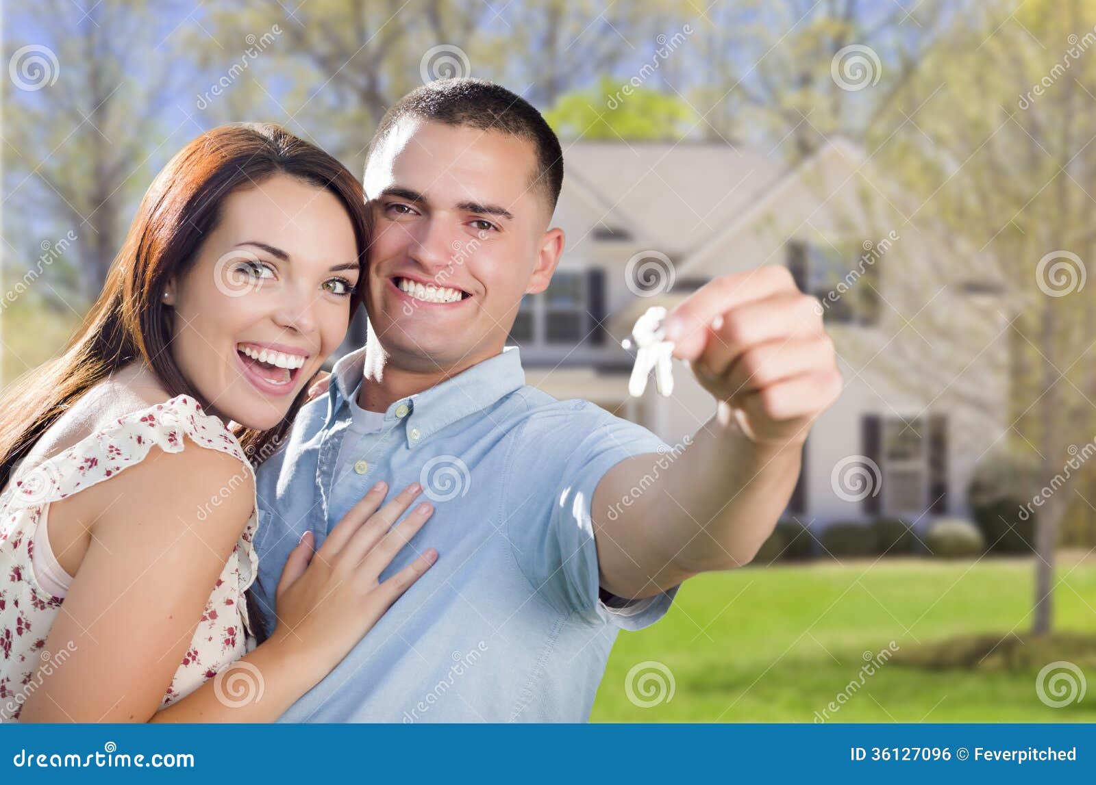 military couple with house keys in front of new home