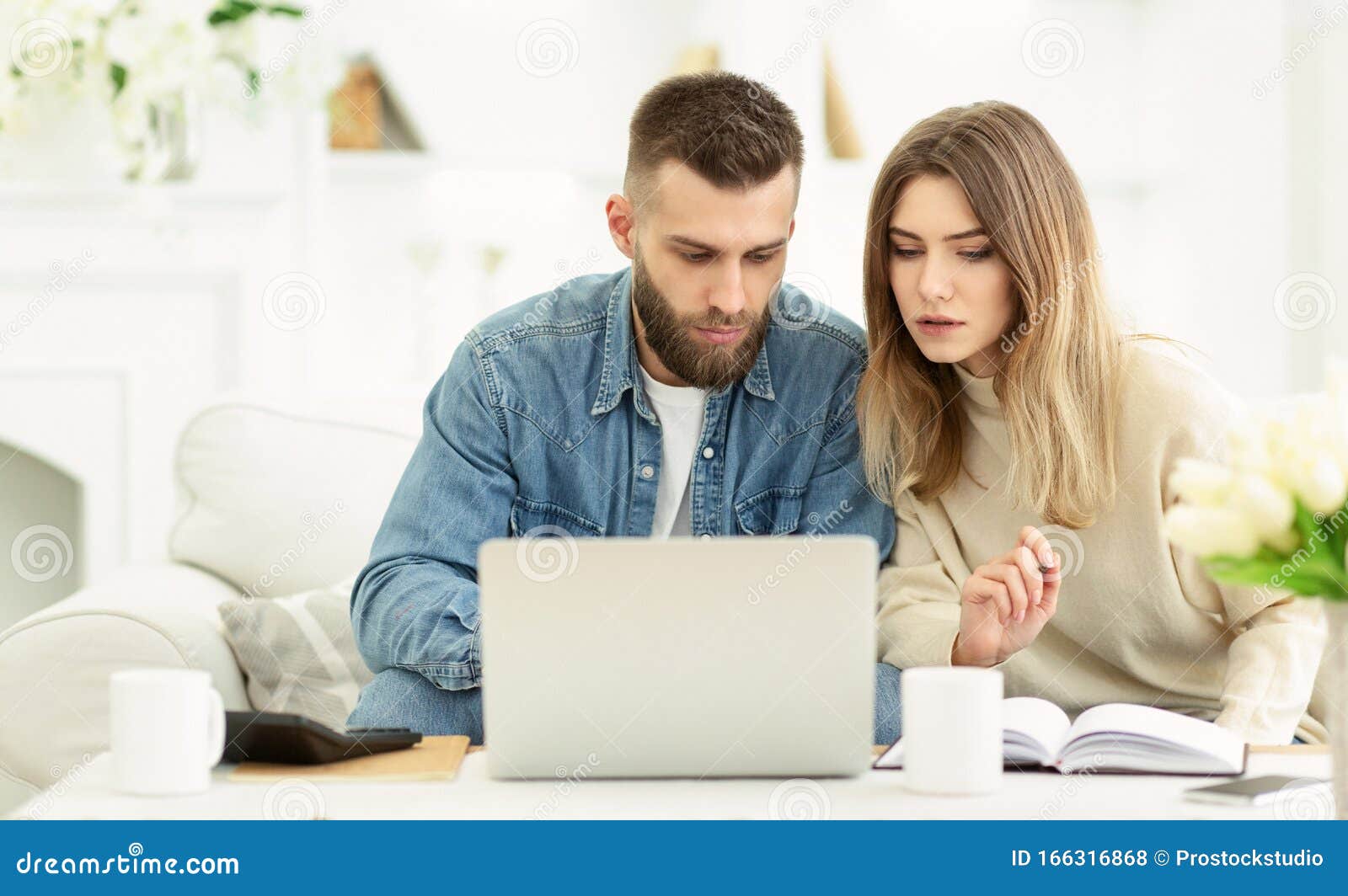 millennial couple managing expenses with laptop and making notes