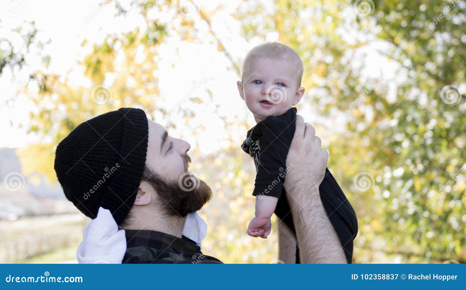 millennial dad holding baby daughter up showing affection