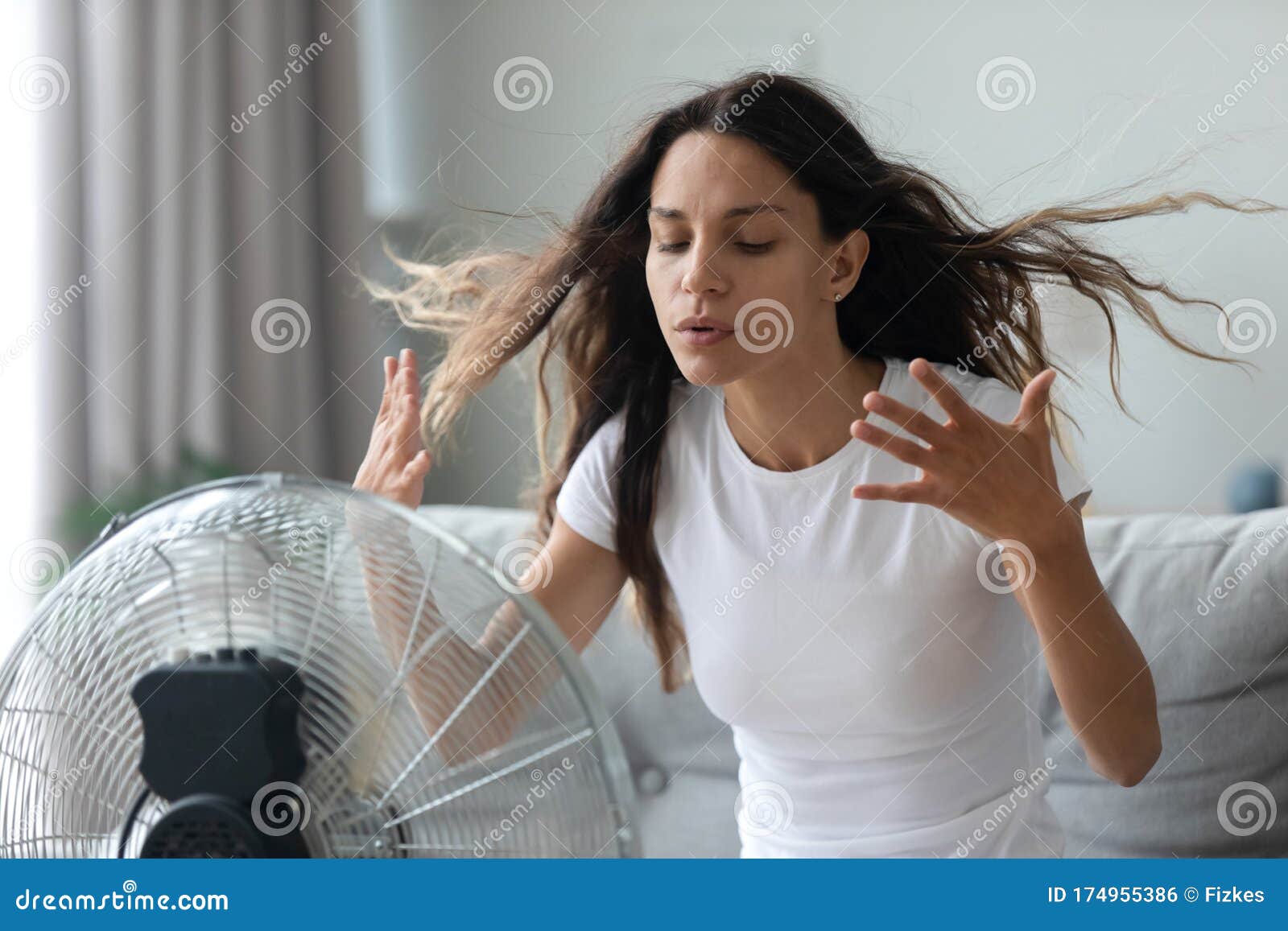 millennial girl suffer from hot weather use floor fan