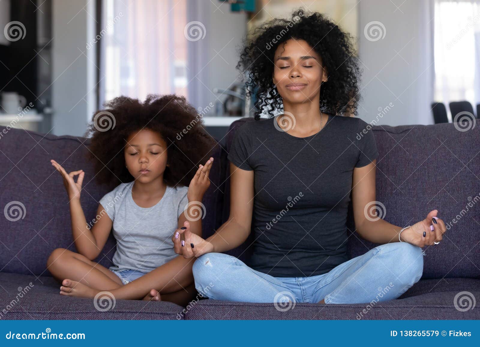 mindful african mom with funny kid daughter doing yoga together