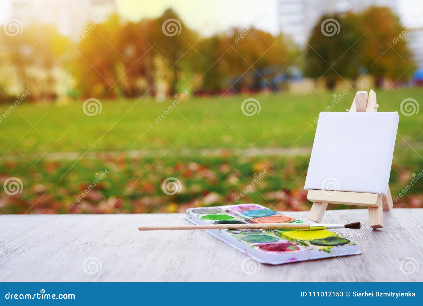 Artist paintbrushes, paint tubes and small easel with canvas