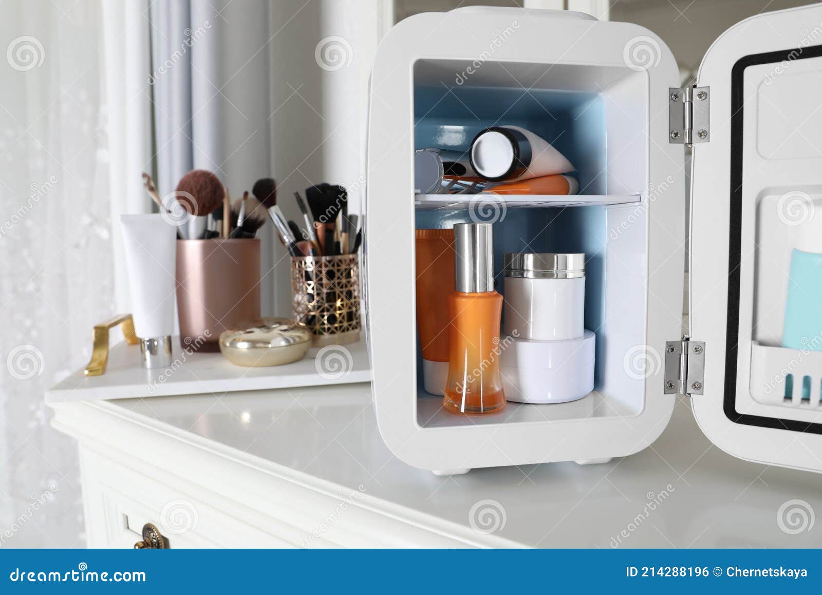 Mini Fridge with Cosmetic Products on White Vanity Table Stock Photo