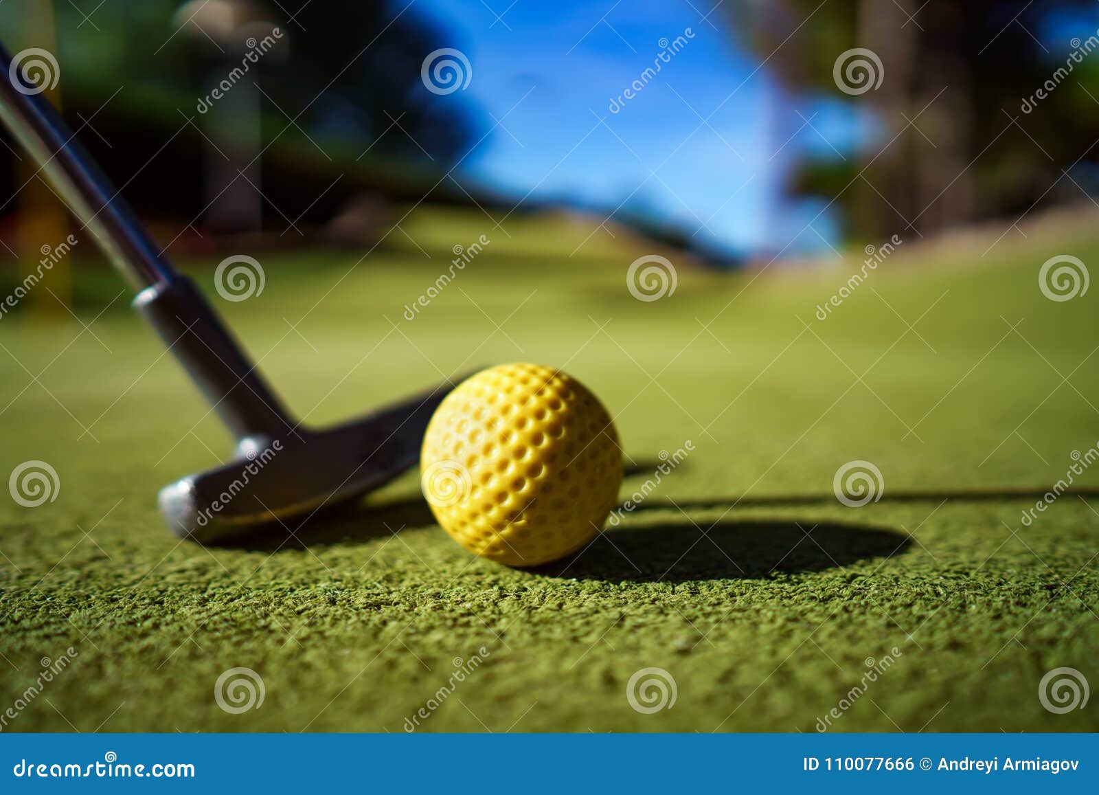 mini golf yellow ball with a bat at sunset