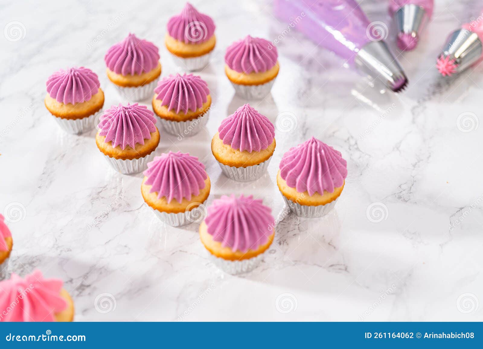 Mini Vanilla Cupcakes With Pink Buttercream Frosting Stock Photo mini-vanilla-cupcakes-with-pink-buttercream-frosting-stock-photo