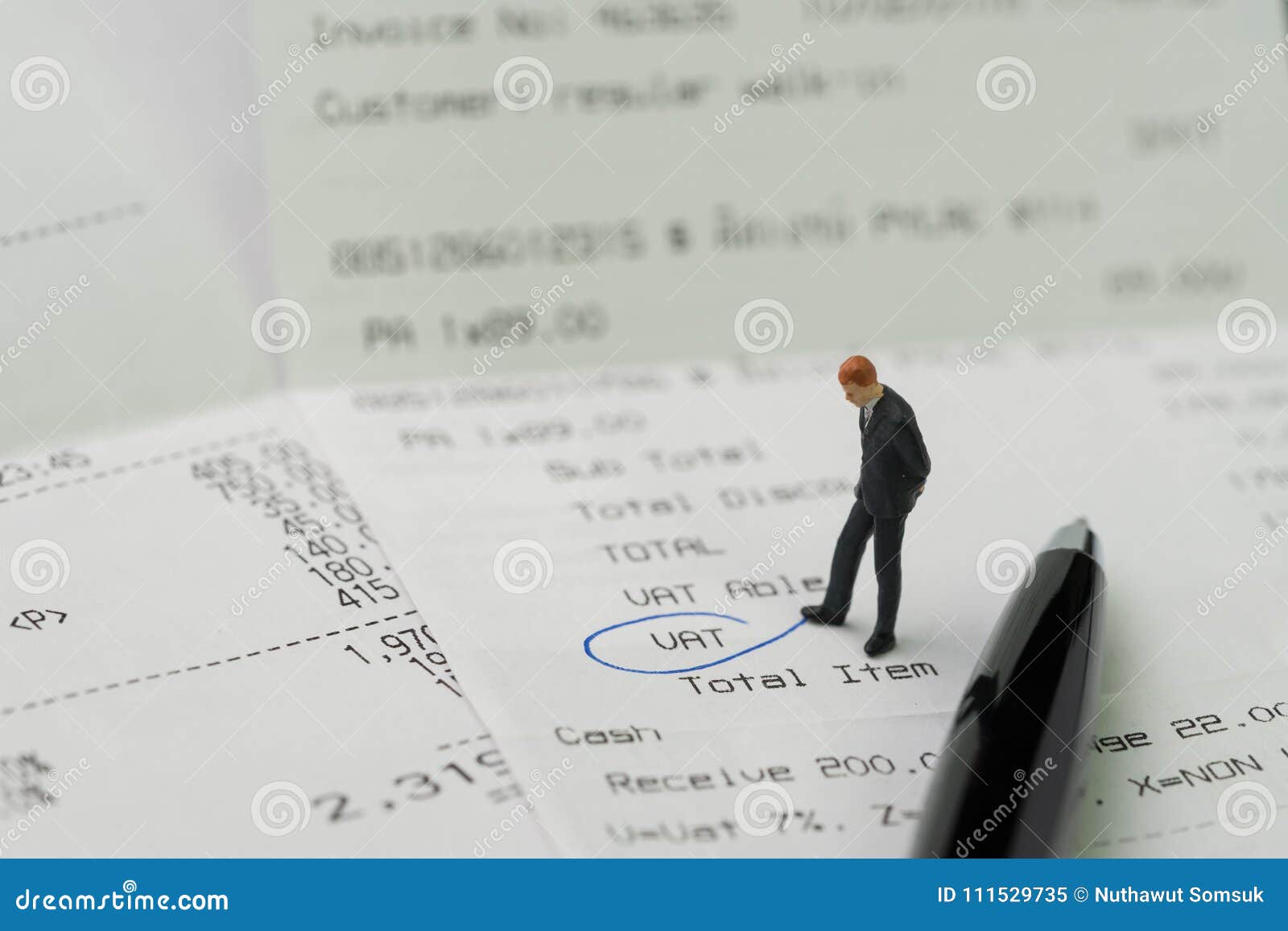 miniature business man figurine standing on printed payment invoice, bill or receipt and looking at vat with pen circle using as