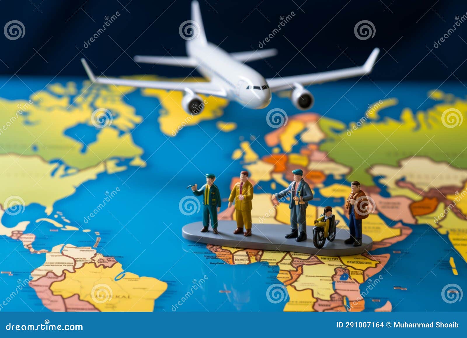 miniature figures, representing male and female travelers, stand near a world map and airplane