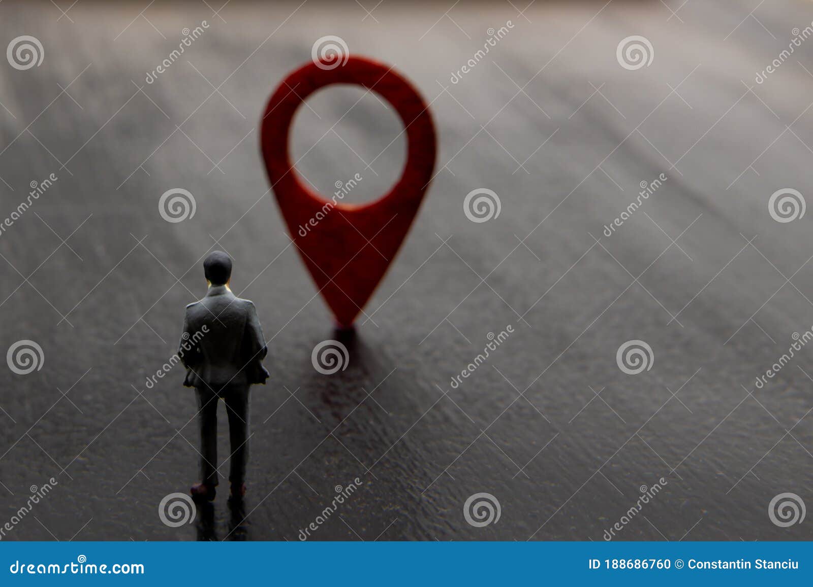 miniature figurine posed as standing visualising businessman making decision on direction to reach destination marked by red