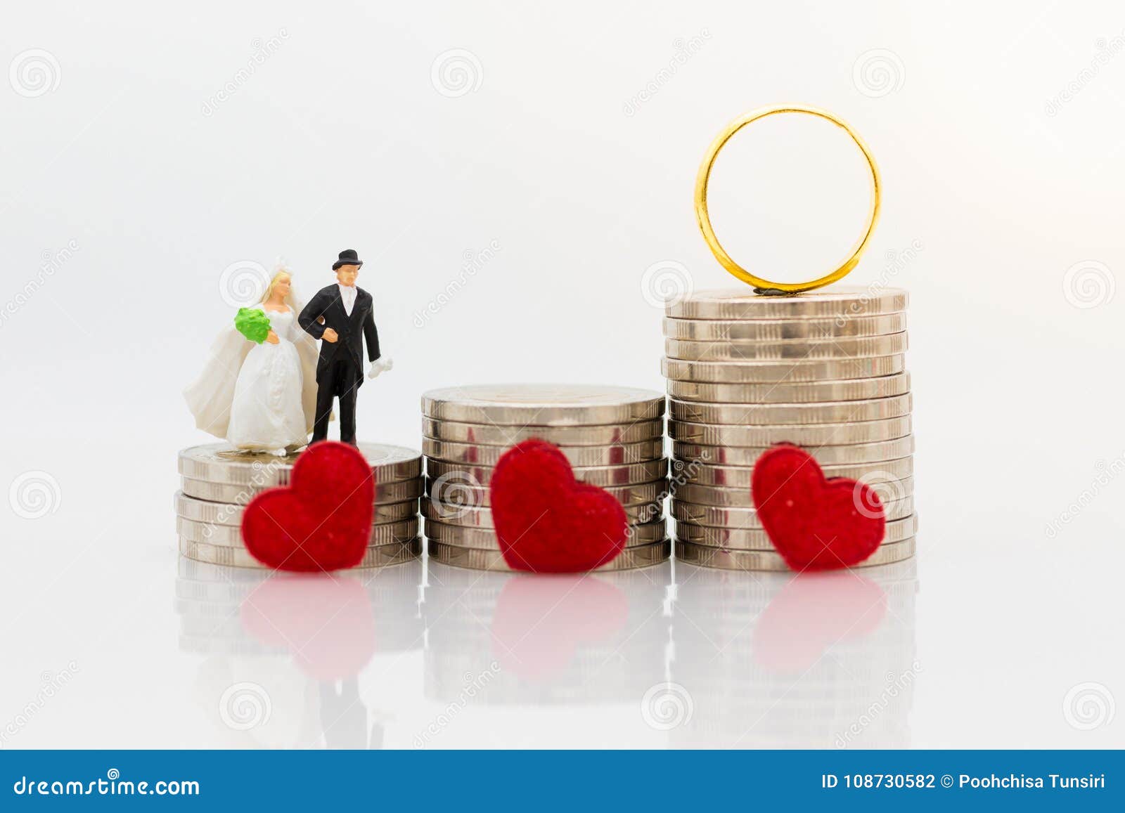 miniature people : bride and groom standing on stack of coins with wedding rings. image use for saving money for marry, accumulate