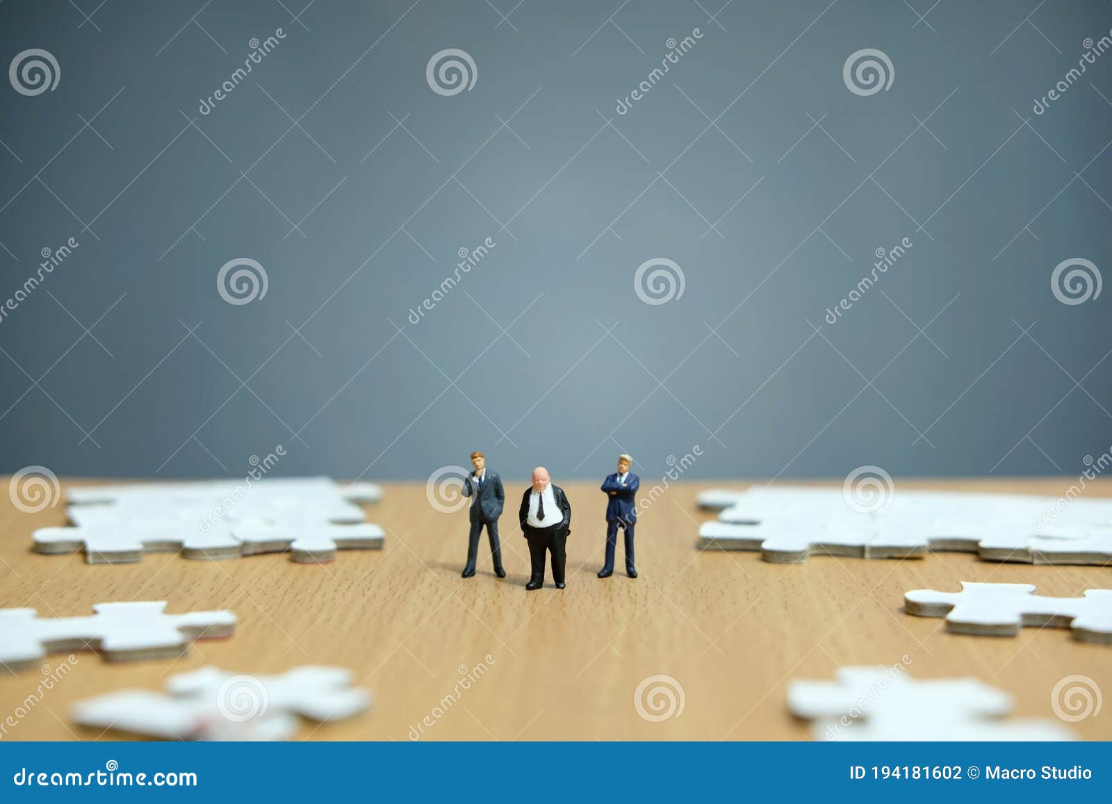 miniature people businessmen standing in front of uncomplete jigsaw puzzles