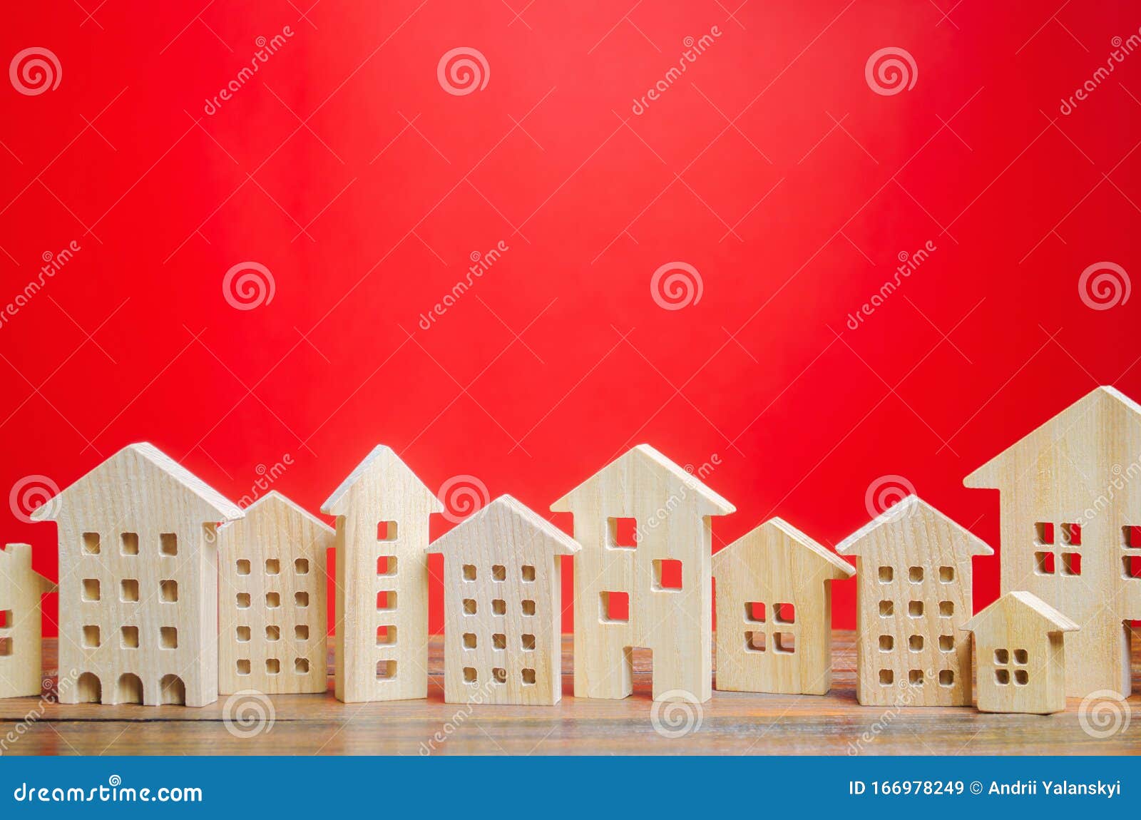 miniature wooden houses on a red background. real estate concept. city. agglomeration and urbanization. market analytics. demand