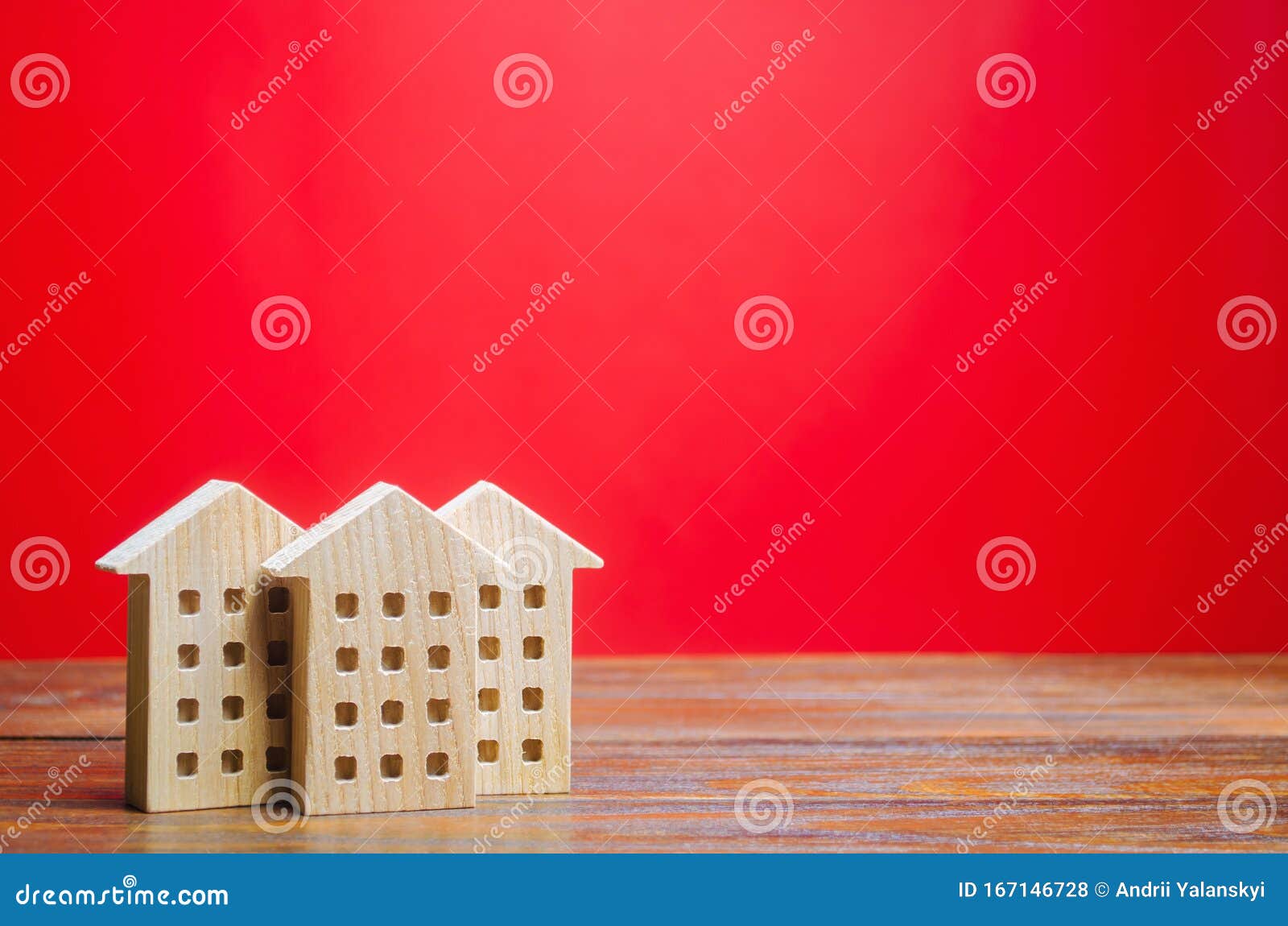 miniature wooden houses on a red background. real estate concept. city. agglomeration and urbanization. market analytics. demand