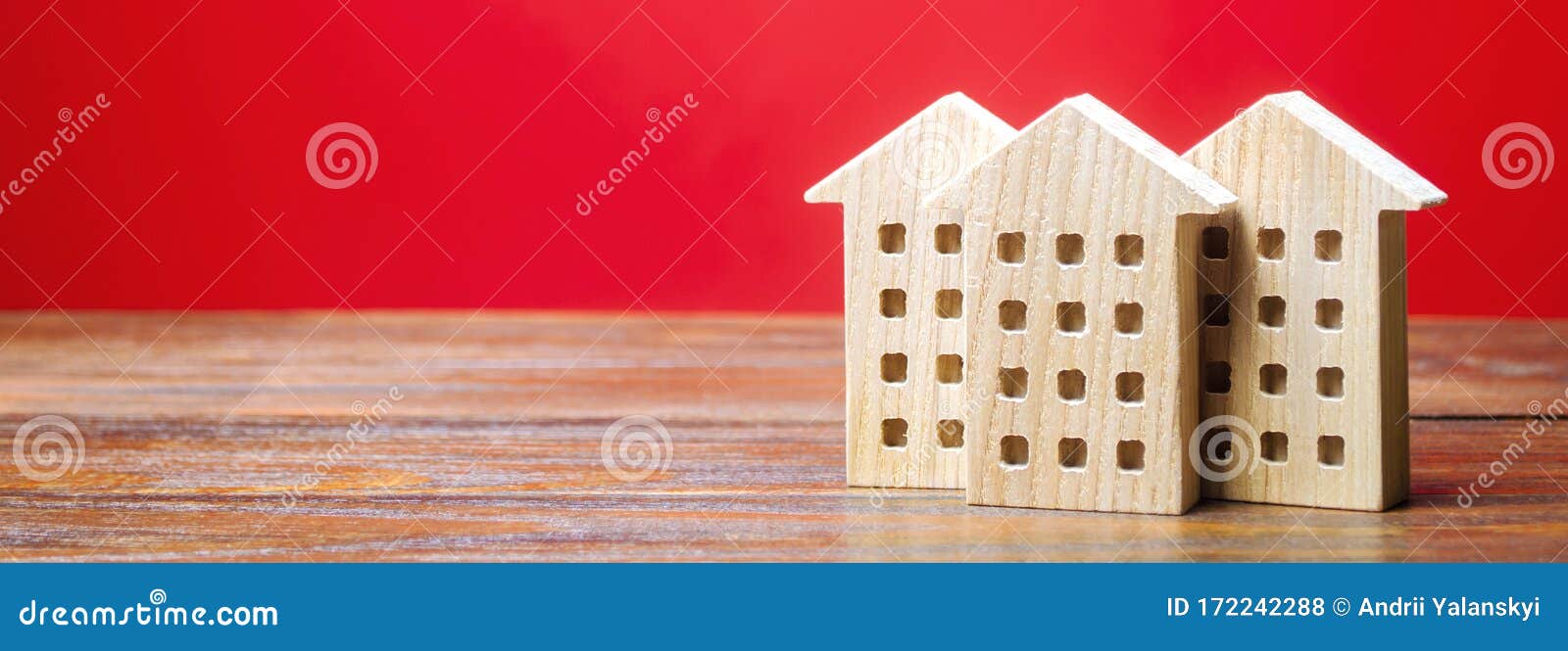 miniature wooden houses on a red background. real estate concept. city. agglomeration and urbanization. market analytics. demand